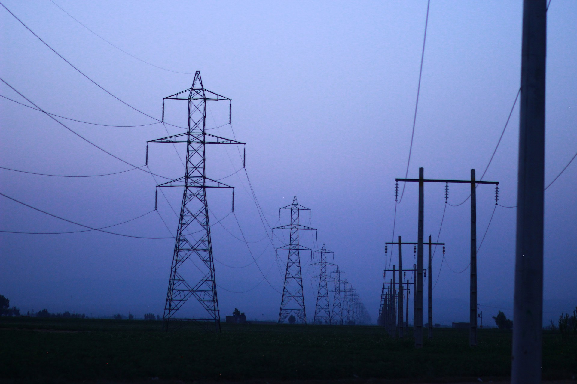 Lignes électriques à haute tension au crépuscule, illustrant la vulnérabilité des infrastructures critiques